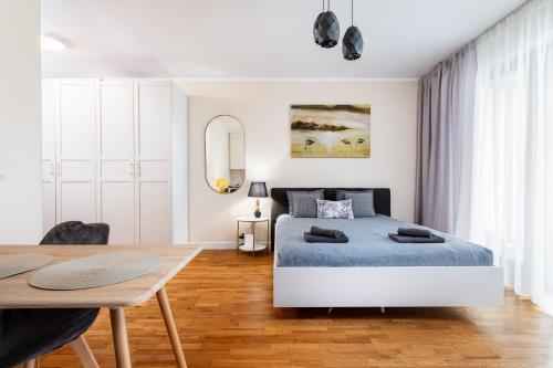 a white bedroom with a bed and a wooden table at Business Suites Arkadia by VAYA STAYS in Warsaw