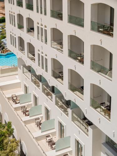 an external view of a white building with tables and chairs at Creta Star Hotel - Adults Only in Skaleta