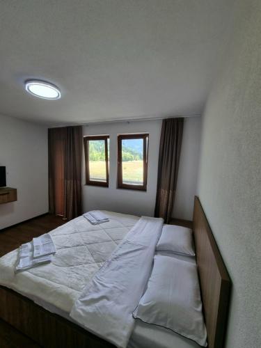 a bedroom with a large bed with two windows at Guesthouse Rama in Valbonë