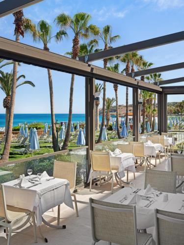 a restaurant with white tables and chairs and the ocean at Creta Star Hotel - Adults Only in Skaleta