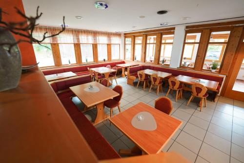 an empty restaurant with tables and chairs and windows at Hotel Sonnenhof - Tante ALMA`s Sommerfrische in Sonnen