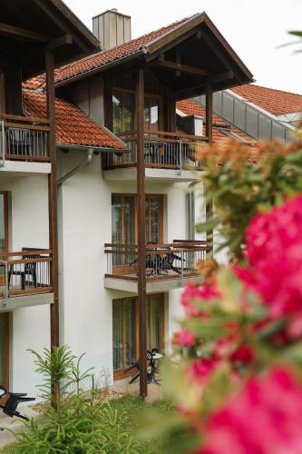 a building with balconies and tables and pink flowers at Hotel Sonnenhof - Tante ALMA`s Sommerfrische in Sonnen