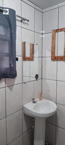 a white sink in a white tiled bathroom at Casa de Campo in Santo André