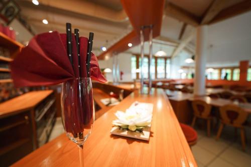 a vase with a red flower on a table at Hotel Sonnenhof - Tante ALMA`s Sommerfrische in Sonnen
