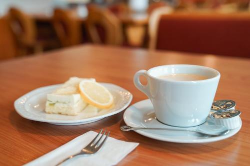a cup of coffee and a piece of cake on a table at Hotel Sonnenhof - Tante ALMA`s Sommerfrische in Sonnen