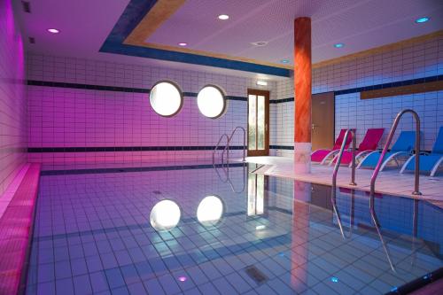 a swimming pool with purple lighting and pink chairs at Hotel Sonnenhof - Tante ALMA`s Sommerfrische in Sonnen