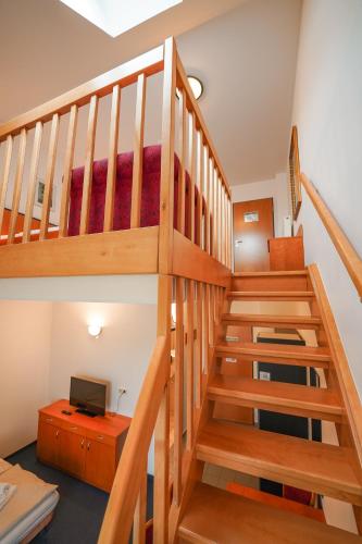 a wooden staircase in a room with a television at Hotel Sonnenhof - Tante ALMA`s Sommerfrische in Sonnen
