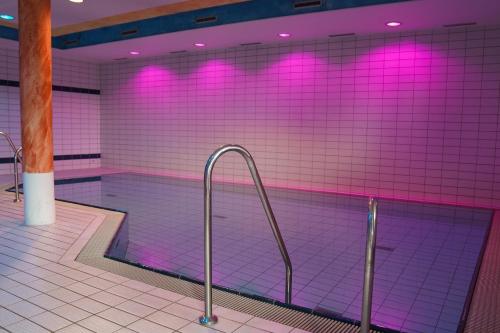 a swimming pool with pink lights in a building at Hotel Sonnenhof - Tante ALMA`s Sommerfrische in Sonnen