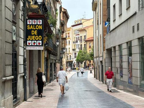a group of people walking down a city street at La Cámara del Ayuntamiento de Oviedo in Oviedo