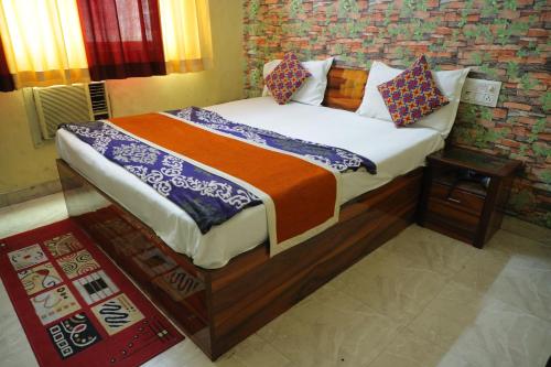 a bedroom with a bed with an orange and blue blanket at Hotel Shri Bhaskar in Bareilly
