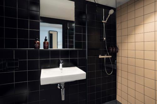 een zwart betegelde badkamer met een wastafel en een douche bij The Social Hub Porto in Porto