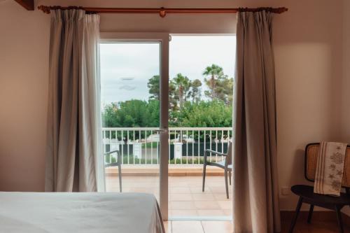 a bedroom with a bed and a sliding glass door at Villas Amarillas in Cala Blanca