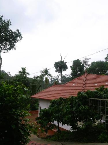 a house with a red roof and some trees at Suvi Homestay - Coorg in Ammatti