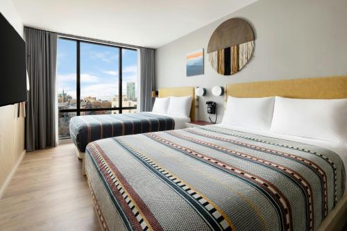 a hotel room with two beds and a large window at Moxy Asheville in Asheville