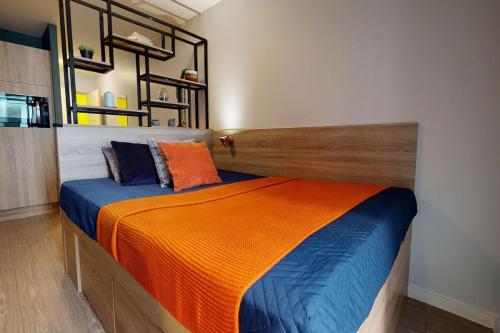 ein Schlafzimmer mit einem Bett mit einer orangen und blauen Decke in der Unterkunft Student Only Bronze Studio Plus at Hammersmith Residence in London