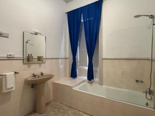 a bathroom with a tub and a sink and a blue curtain at Casa Senhor da Pedra in Vila Franca do Campo
