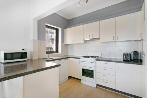 a kitchen with white cabinets and a stove top oven at Ultimate Bondi Escape #2 Stunning Views ! in Sydney