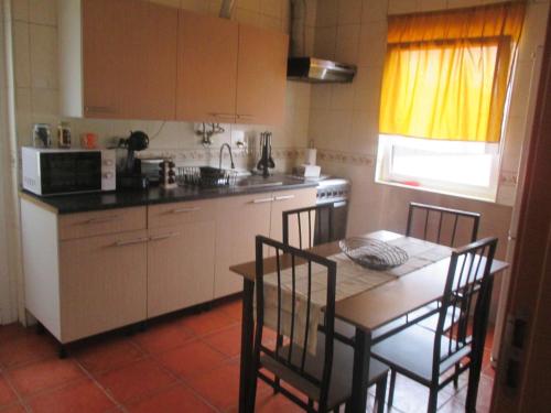a kitchen with a table and chairs and a table and a table and a kitchen at Casa dos avós in Canas de Senhorim