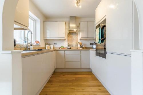a kitchen with white cabinets and a wooden floor at 3 Bed in Baconsthorpe oc-s32338 in Baconsthorpe