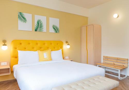 ハイデラバードにあるBloom Hotel - Jubilee Hillsのベッドルーム(黄色のヘッドボード付きの大きな白いベッド1台付)