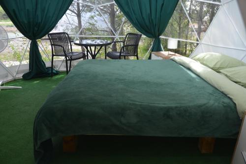 a bed in a tent with chairs and a table at Глемпінг Zatuшшя in Berezovka