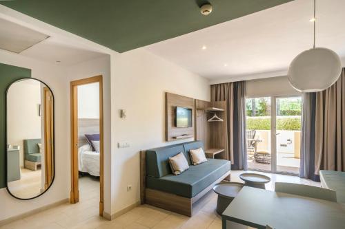 a living room with a blue couch and a bedroom at Cabot Tres Torres Apartamentos in Playa de Palma