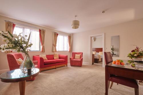 a living room with red chairs and a table at Kings Park Hotel in Retford