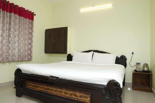 a bedroom with a bed with white sheets at Cozy Heaven in Ooty