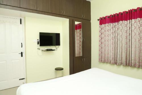 a bedroom with a bed and a tv on the wall at Cozy Heaven in Ooty