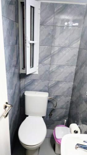 a bathroom with a toilet and a window and a sink at Kipseli Rooms in Athens