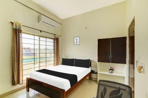Un dormitorio con una cama y una ventana y una silla. en Super Hotel O Chikmangaluru Near Railway Station, en Chikmagalur
