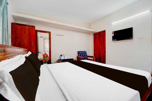a bedroom with a bed with red curtains and a tv at Hotel O Sun Set View Ooty in Ooty