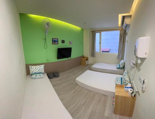 a room with two beds and a green wall at Fire Island Guest House in Green Island