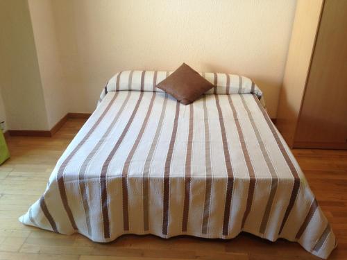 ein Bett mit einer gestreiften Decke und einem Kissen darauf in der Unterkunft SM Apartments in Lleida