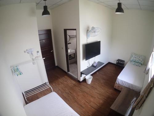 a living room with a television and a bed and a mirror at Fire Island Guest House in Green Island