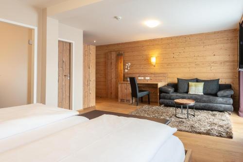 a bedroom with a bed and a couch and a desk at Hotel Dirsch Wellness & Spa Resort in Emsing