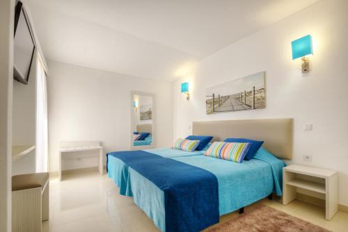 a white bedroom with a blue bed with blue sheets at 3HB Golden Beach in Albufeira