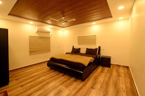 a bedroom with a bed and a wooden floor at Villa NirvanaPool4BHKPatioLawnACParty Villa in Hyderabad