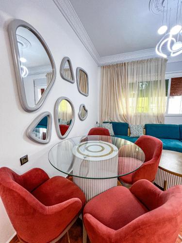 a living room with a glass table and red chairs at Appart-hôtel Costa Azul - Monaco in Oued Laou