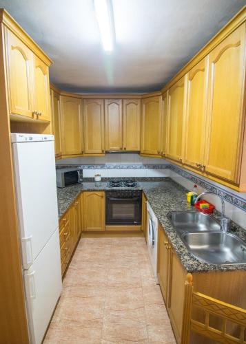a kitchen with wooden cabinets and a white refrigerator at Casa Saura Z in Benasque