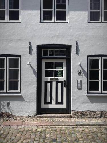 a white building with a door and three windows at Ferienwohnung 3, Schlaf-Gut-Johannis, Flensburg in Flensburg