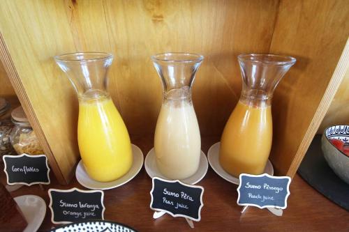 two vases of orange juice on plates on a table at Quinta do Canal in Vila Nova de Milfontes