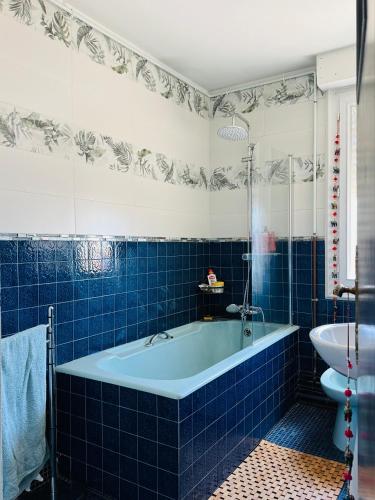 La salle de bains est pourvue de carrelage bleu, d'une baignoire et d'un lavabo. dans l'établissement 24 H Circuit Le Mans, au Mans