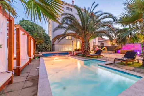a swimming pool with two chairs and a palm tree at Apartments Bracic Spa in Sukošan