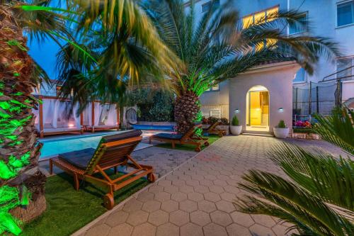 a house with a swimming pool and palm trees at Apartments Bracic Spa in Sukošan