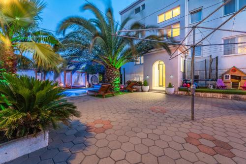 a courtyard with palm trees and a building at Apartments Bracic Spa in Sukošan