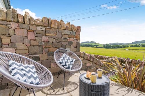 two chairs and a table on a patio with a stone wall at 2 Bed in Newburgh oc-f32595 in Newburgh