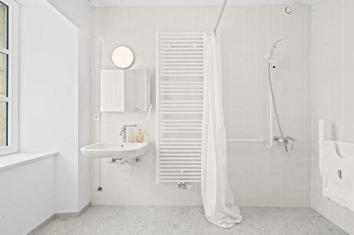 a white bathroom with a sink and a shower at Gîte Lasauvage 83 in Differdange