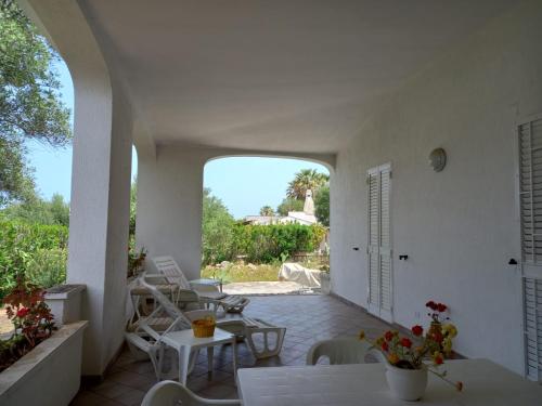 an outdoor patio with tables and chairs and an archway at Hotel Masseria Tutosa in Ostuni