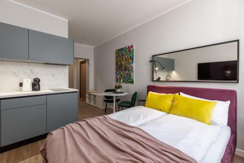 a bedroom with a bed with yellow pillows and a kitchen at P6-A Riga Old Town Apartments in Rīga